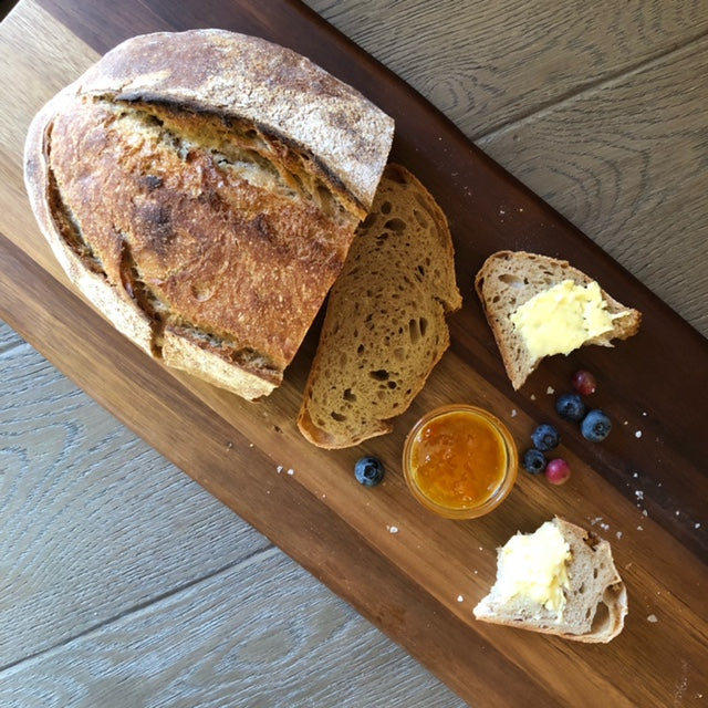 Sliced loaf of bread from Maritime Bread Co on a cutting board with jam and berries